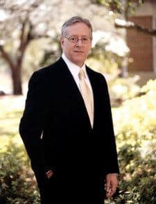 Joe Aguillard in a suit with his hand in his pocket