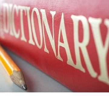 Spine of a red dictionary with a pencil next to it.