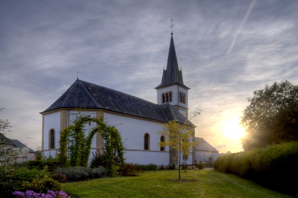 White church against a sunrise sky with whispy clouds