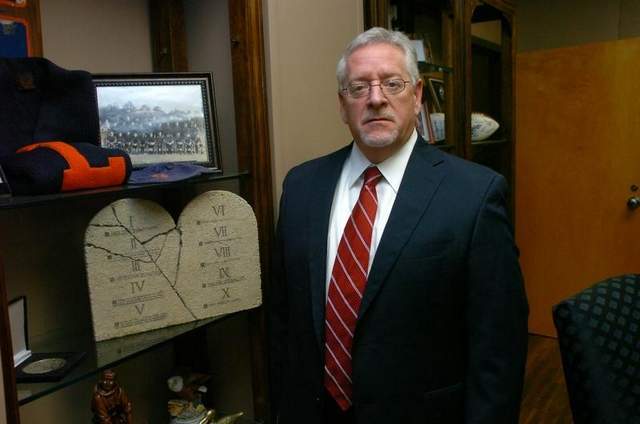 Dr. Joe Aguillard in his office standing next to a 10 commantments plaque