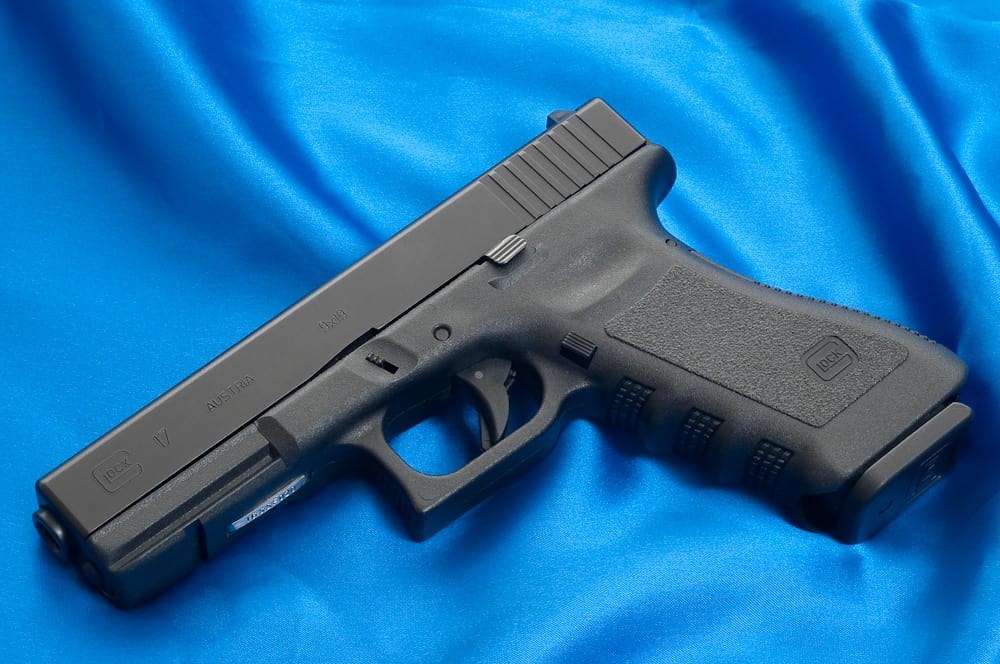 A Glock 17 sits on blue satin fabric