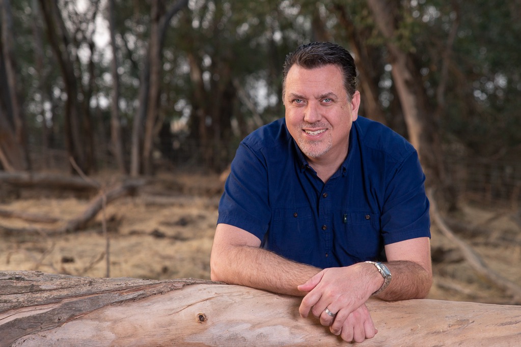 Rondall Reynoso is shown in an Eucalyptus grove, leaning on a deadfall, on the property on which he was raised.