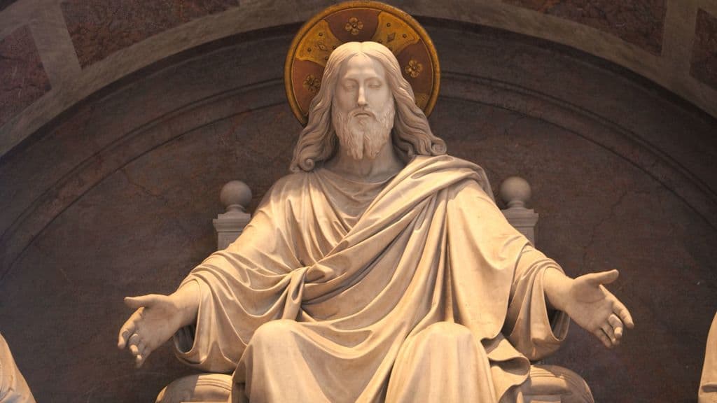 Shown is a stone statue of Jesus with his arms spread in a welcoming gesture.