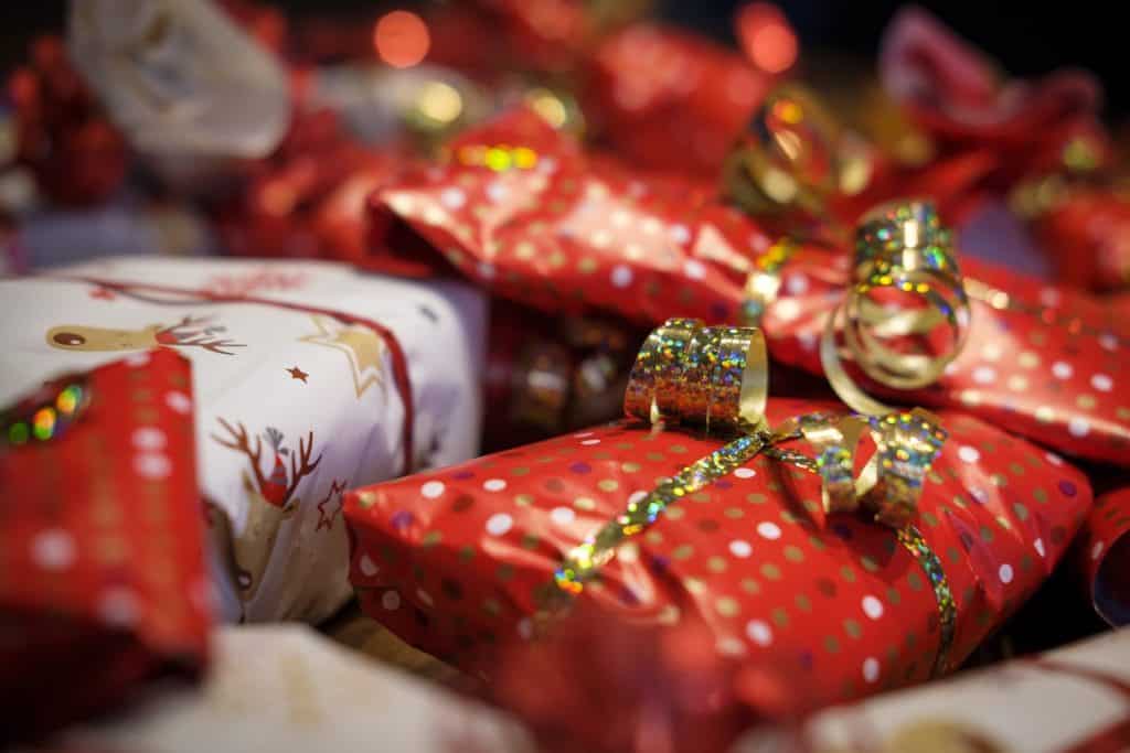 Small gifts wrapped in red and gold paper sit in a pile.