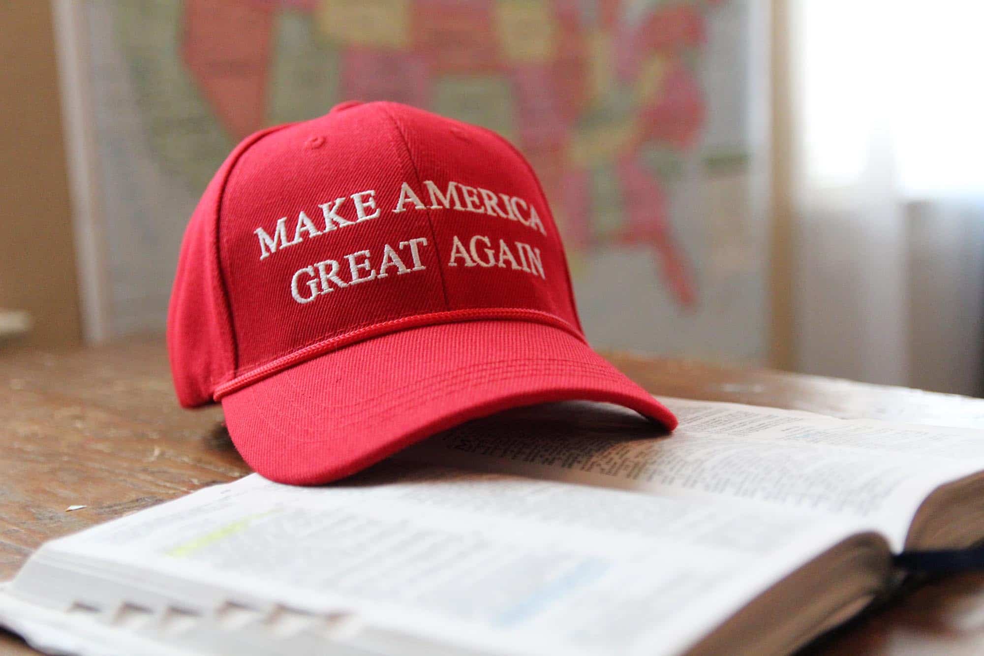 A red baseball cap with "Make America Great Again" sits on an open-faced Bible.
