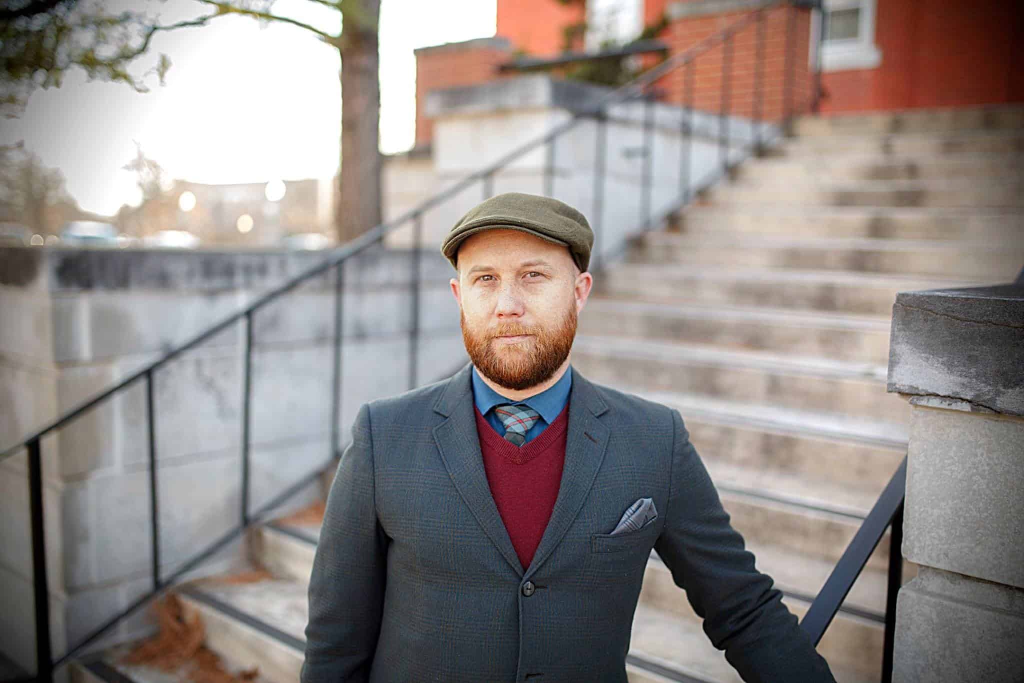 A portrait of Alan Noble standing outside in front of concrete steps.