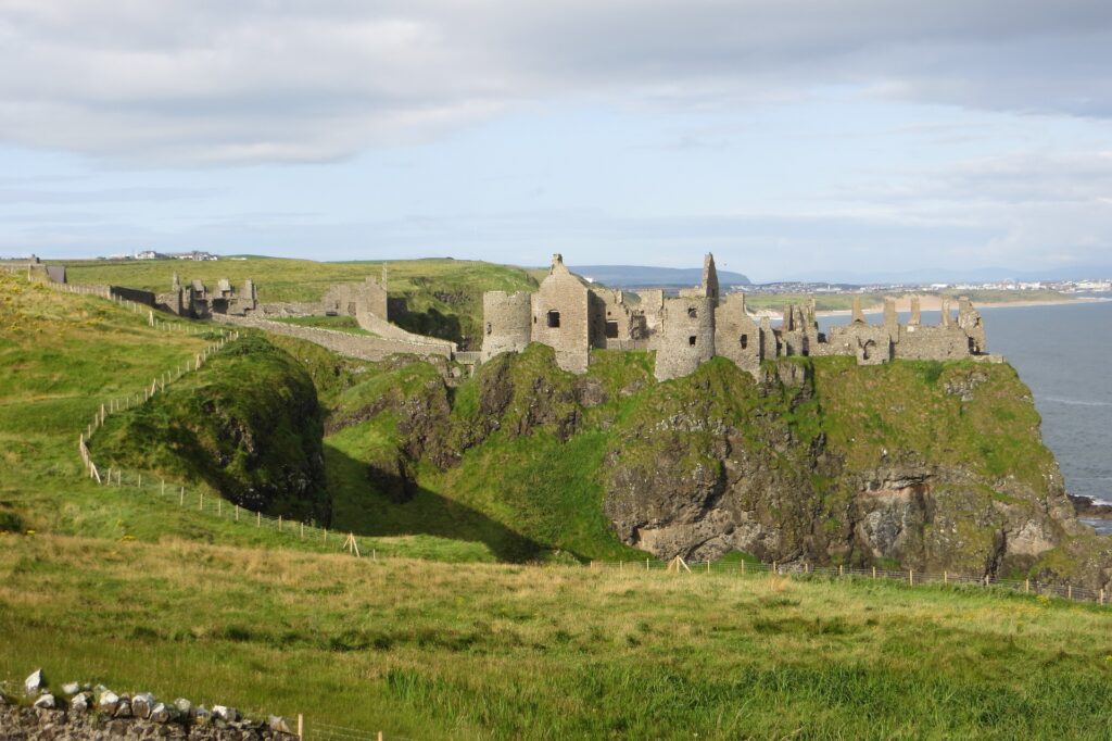 The ruins of Dunluce Castle in Northern Ireland sits on a field of green.