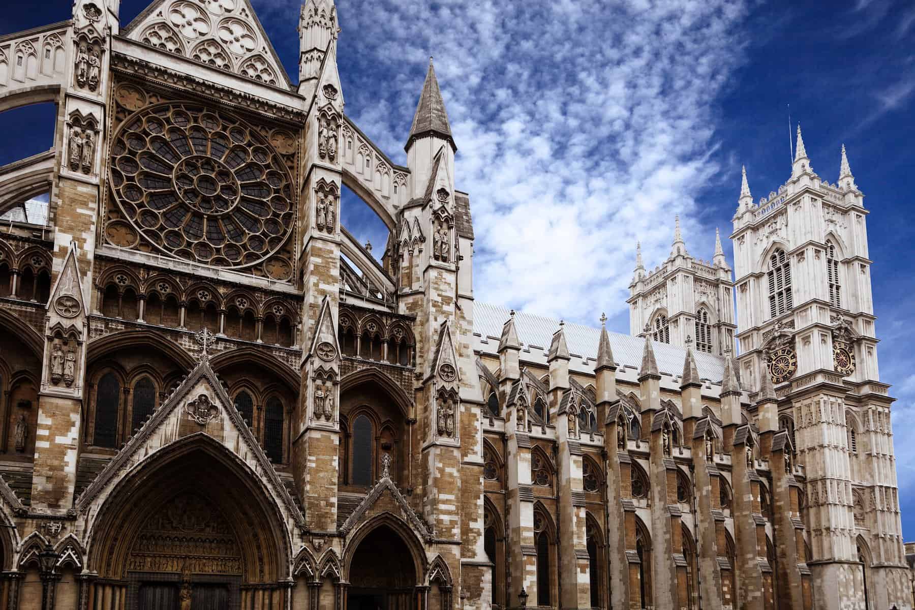 A photo of the top portion of Westminster Abbey with a blue sky with soft clouds behind.