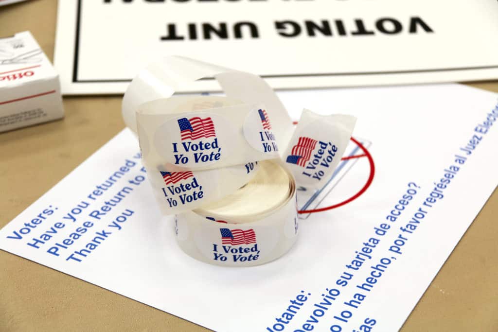 A roll of “I voted” stickers in English and Spanish sits on other voting related paper