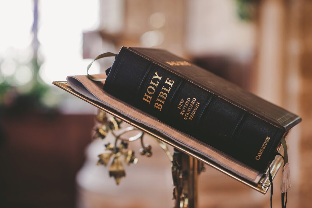 A thick bible sitting closed on a metal lectern in a church