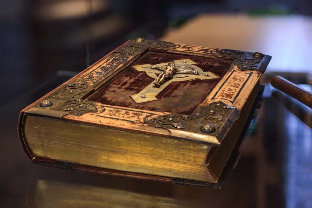 old looking bible with metal corners and a crucifix on the cover laying on a table