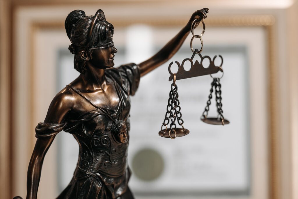 a bronze lady justice is shown from the waist up holding the scales of justice