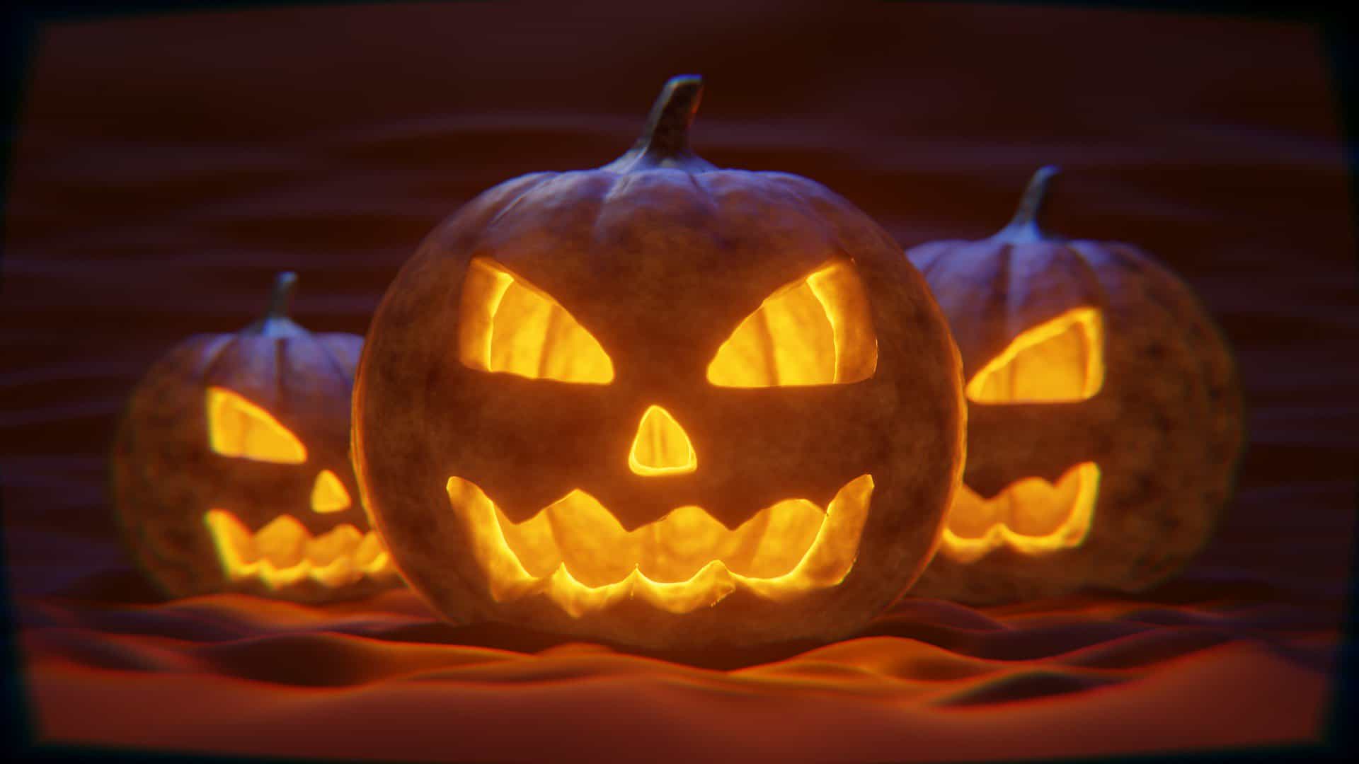 Three carved pumpkins, jack-o'-lanterns, in the dark with light emanating