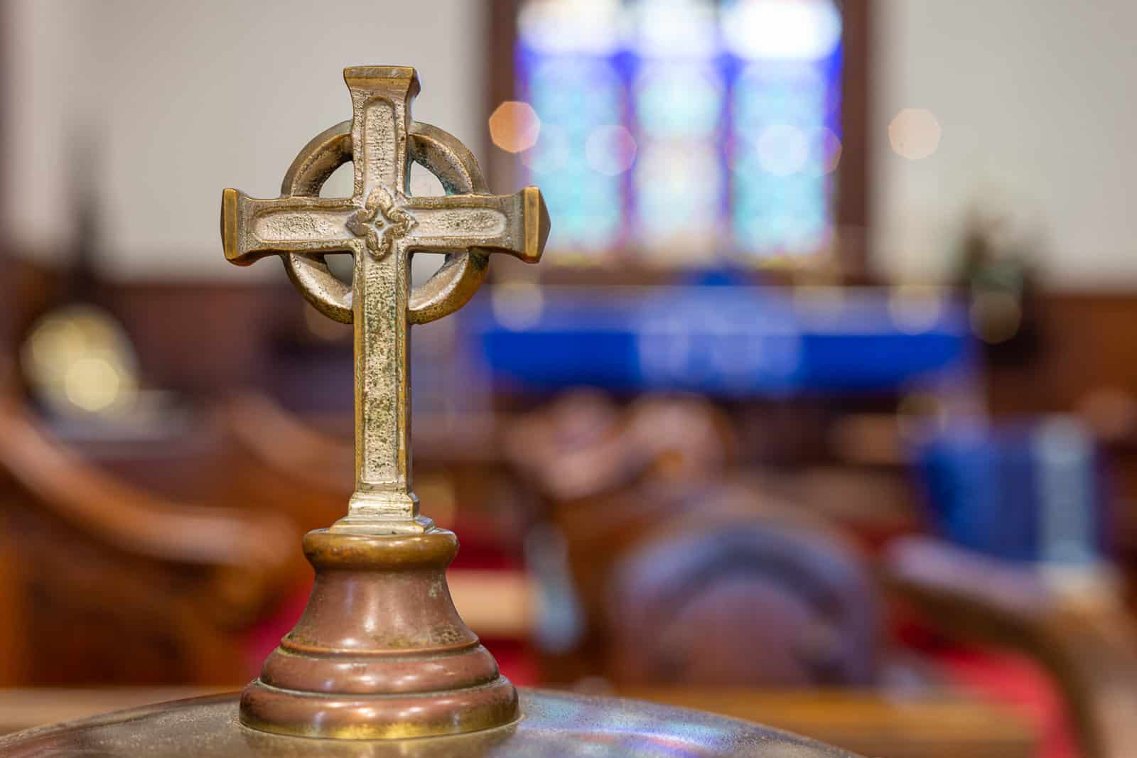 A close-up photo of a metal cross decoration that serves as the handle for an antique baptismal font at St. Luke's Episcopal Church in Cleveland, TN