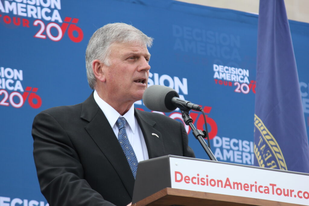 Franklin Graham stands at a podium, speaking, in side profile