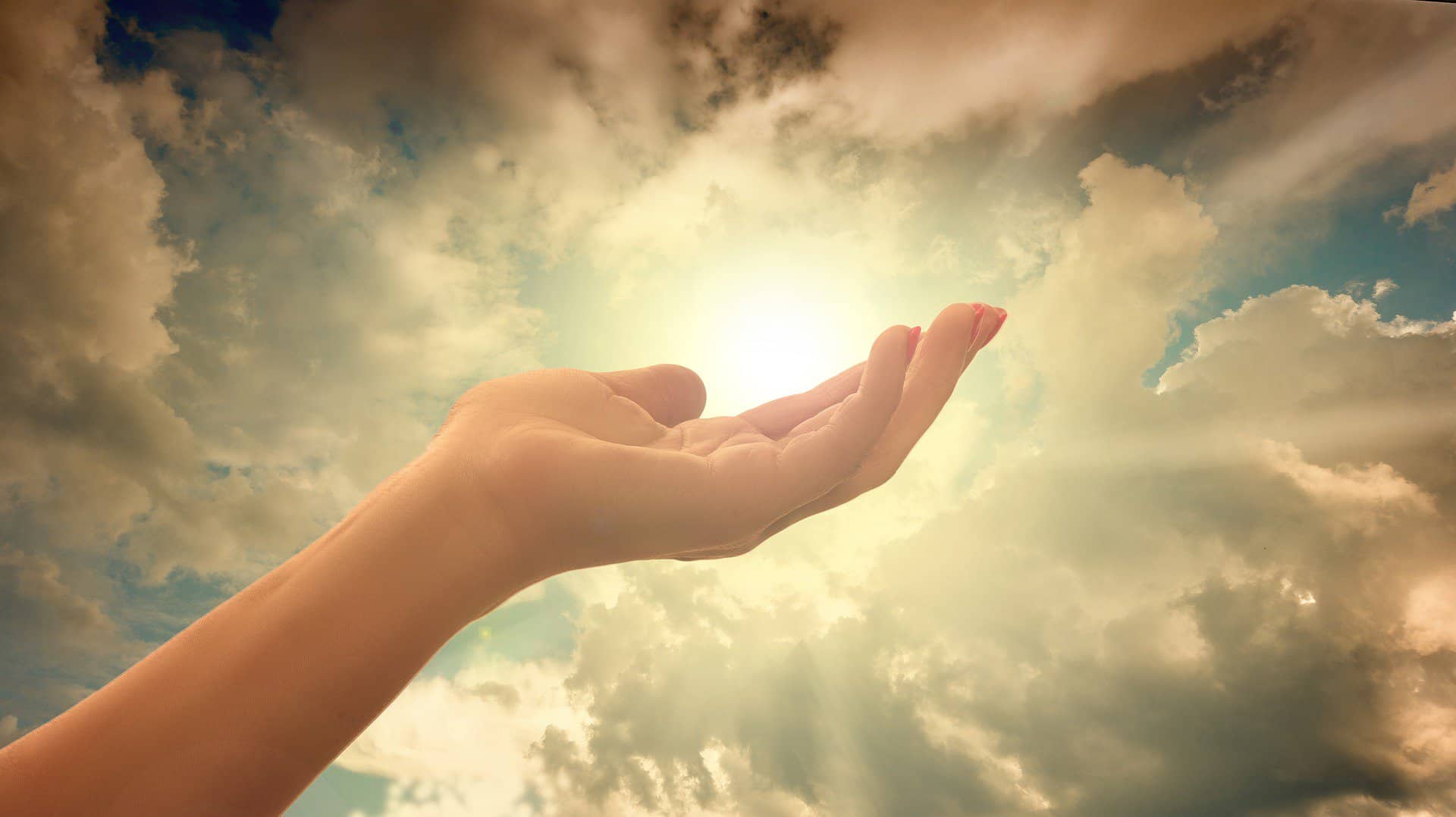 a woman's hand with short red painted nails is shown palm up and fingers relaxed against the backdrop of a sunlit cloud