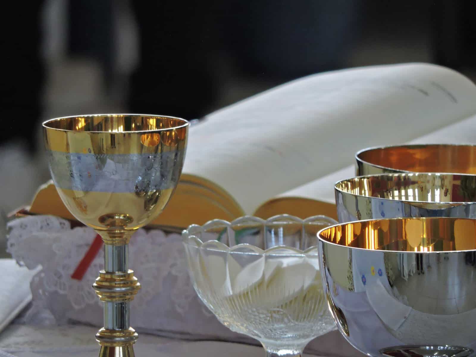 silver chalice, a bible, and a glass bowl with communion bread