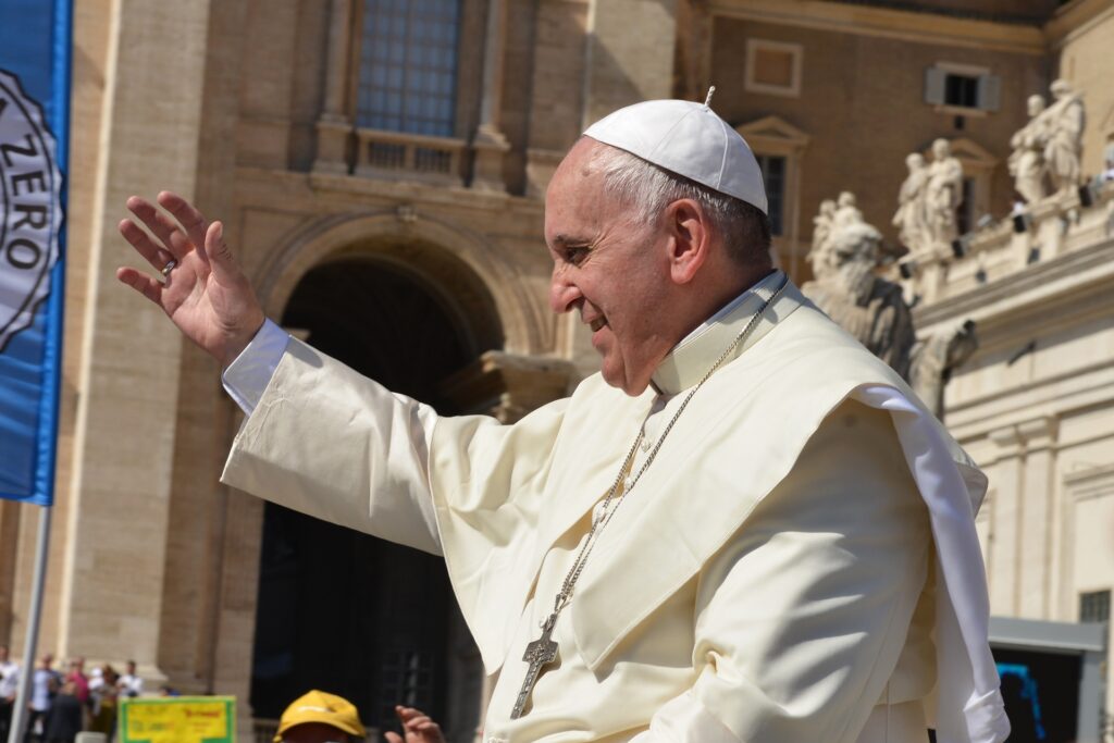 a side photo of the Pope greeting a crowd