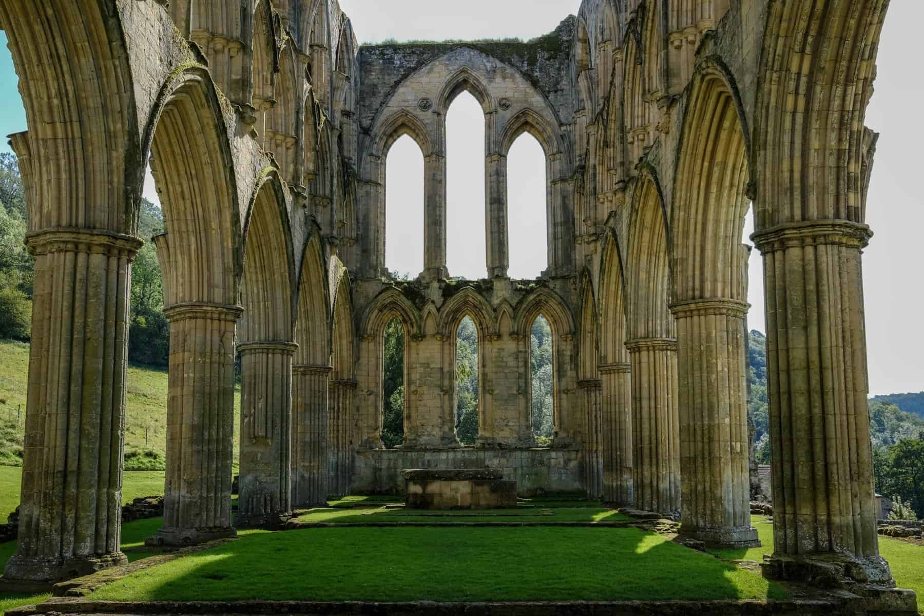 a shell of a stone cathedral surrounded by green grass inside and out