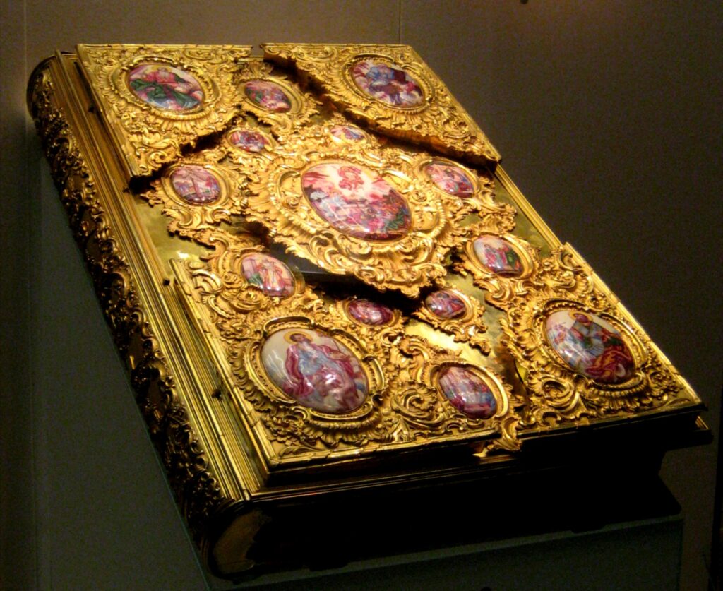 Bible- A beautifully ornate copy of the gospels with a cover made of embossed gold and small possibly ceramic paintings.