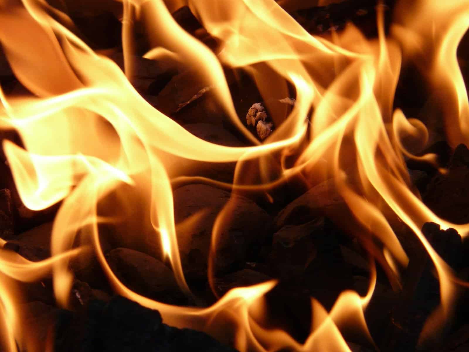 A close up image of a wood fire with orange and yellow flames.