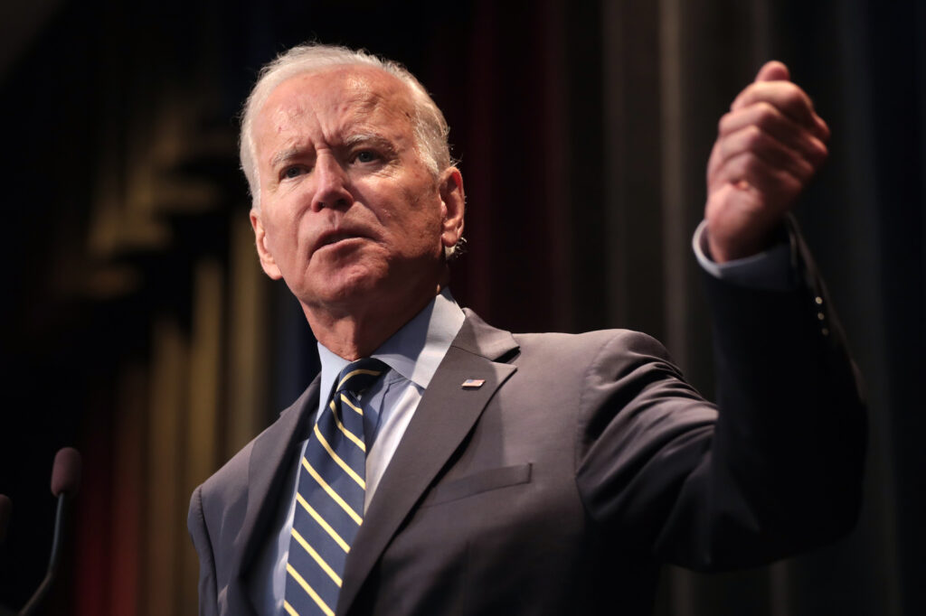 President Joe Biden is shown in a gray suit and speaking at an event.