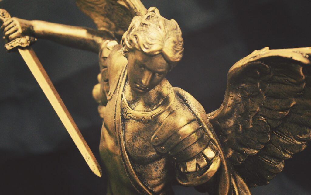 A bronze statue of Michael the Archangel is shown with sword drawn.