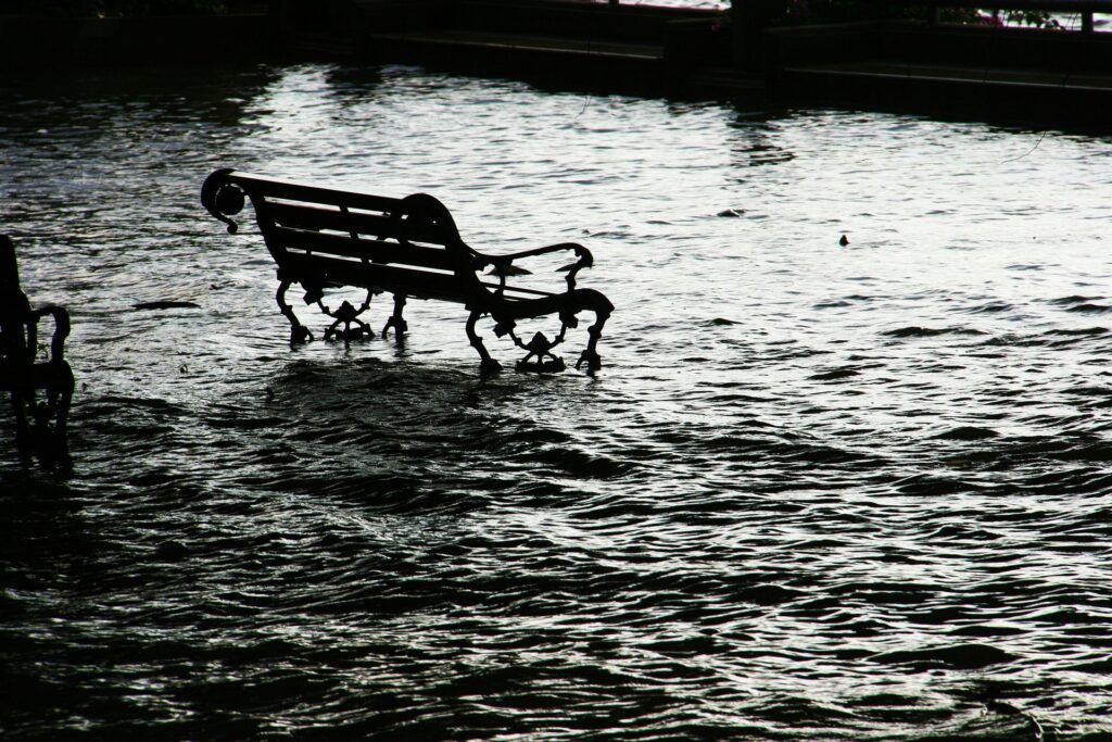 A bench sits surrounded by floodwaters in this black and white image.