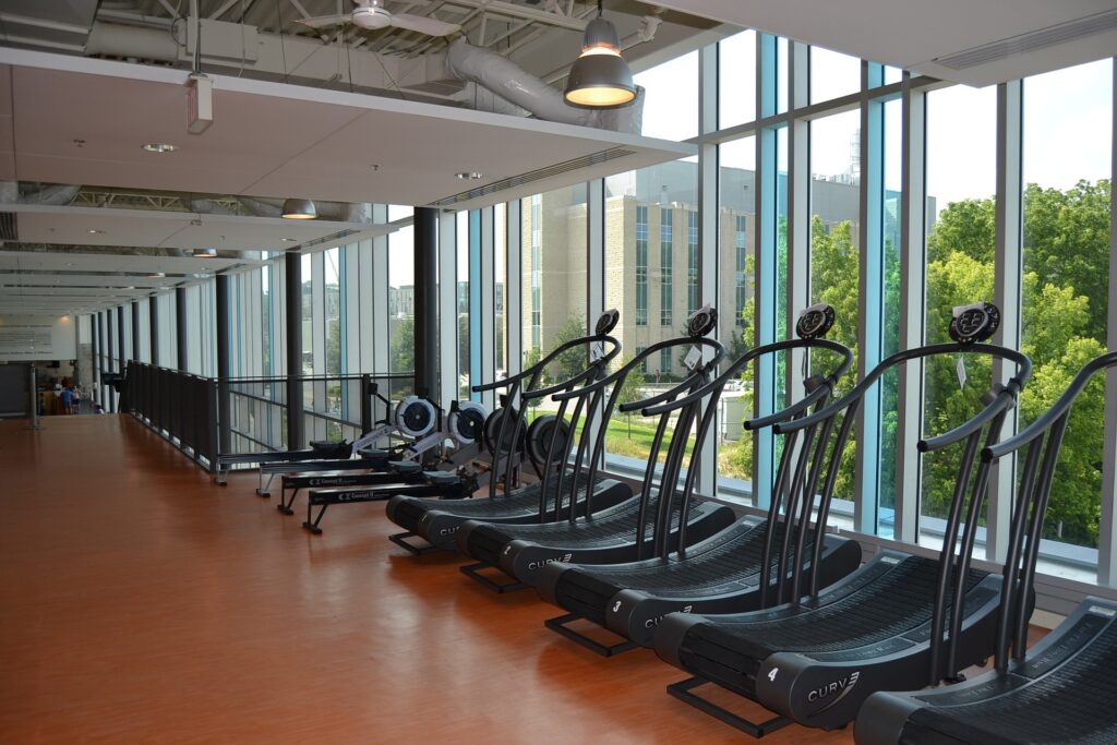 Treadmills are seen lined up facing a window.