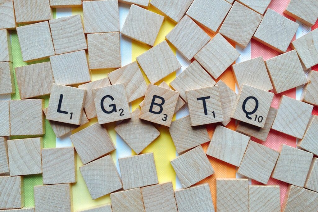 Scrabble tiles are face down on a rainbow table with only the letters LGBTQ facing up.