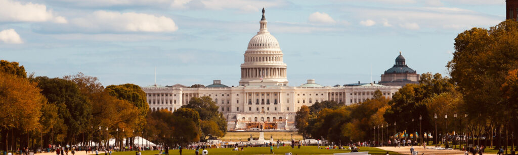 A panoramic image of a street view of the DC capitol dome in warm light.