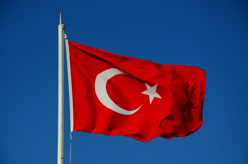 A flag of Turkey waves atop a flagpole.