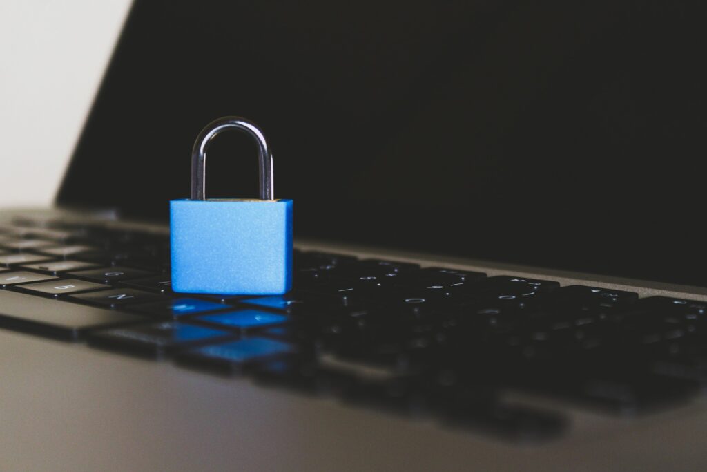 A blue padlock is shown sitting on the keyboard of a laptop.