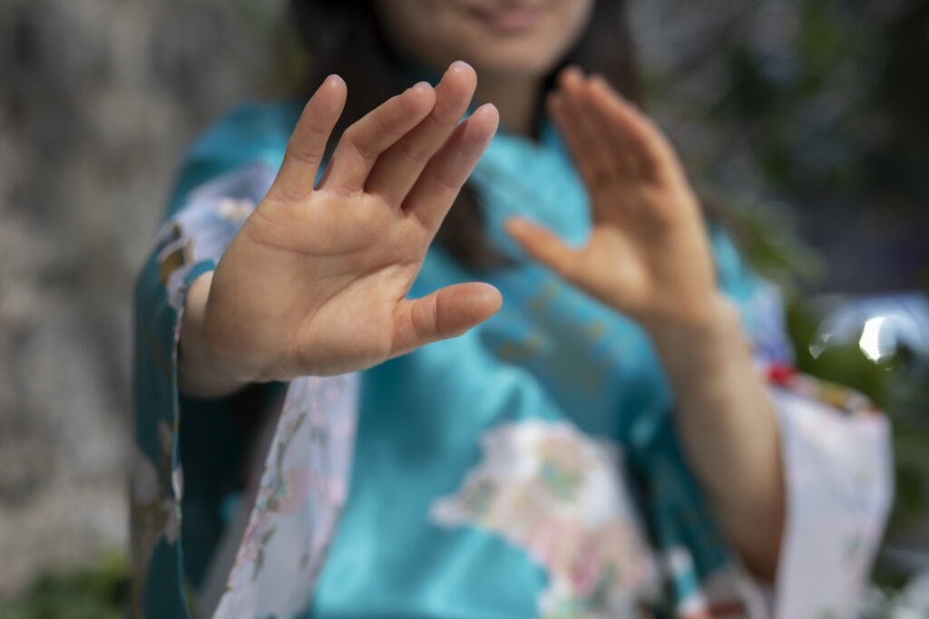 A woman's hands are shown one closer to the camera, one closer to her blurred body.