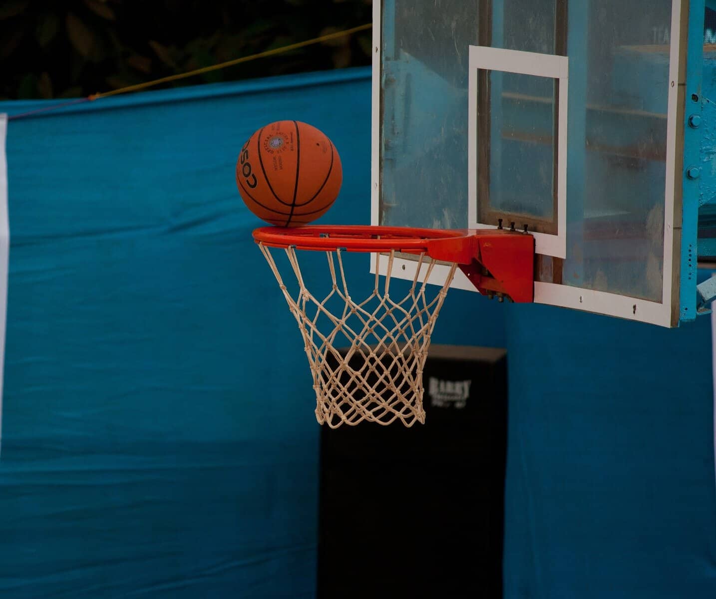 A basketball is seen at the rim of a hoop about to drop in.