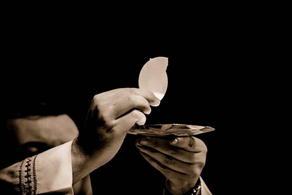 A rector is shown raising the Eucharist wafer above his after blessing communion.