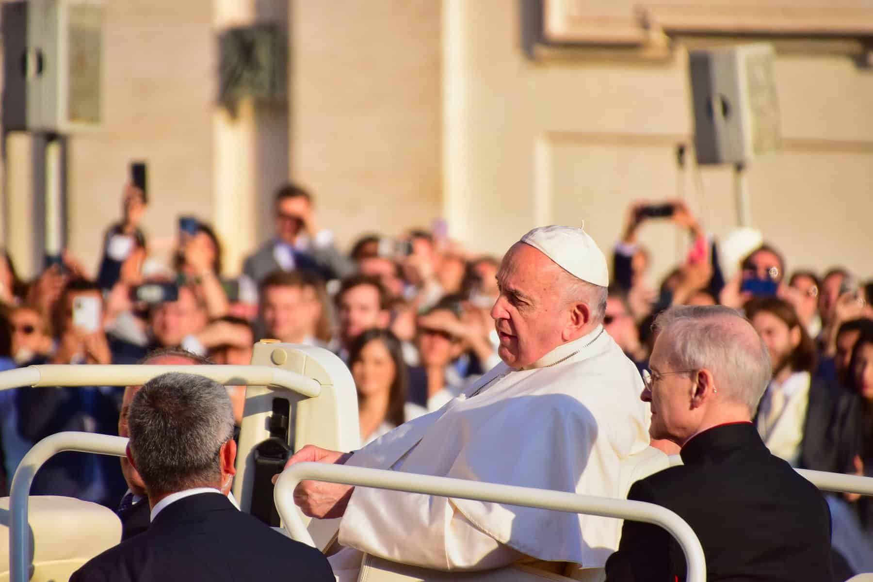 Pope Francis is shown riding through a crowd in the "Pope-mobile".
