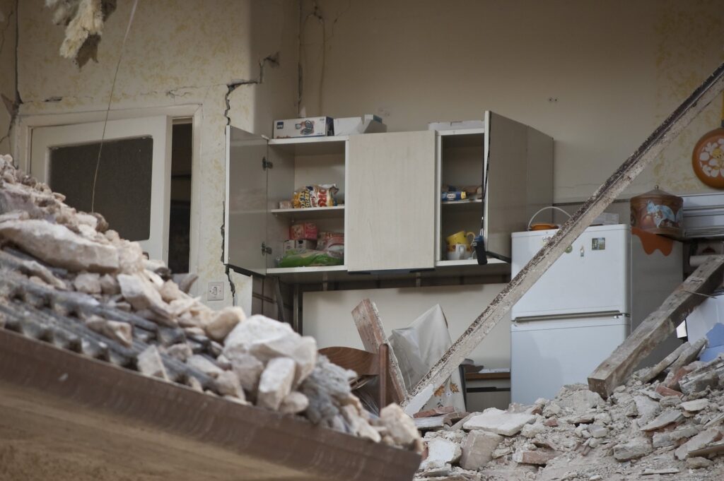 A kitchen is shown with fallen building rubble in it.