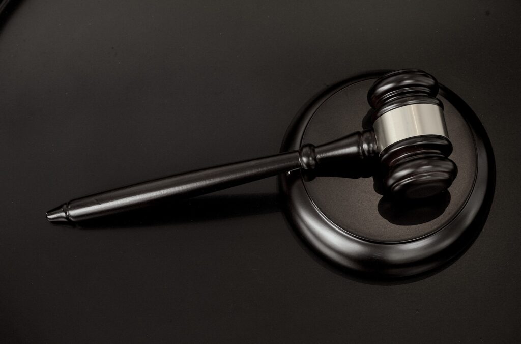 A dark colored judges gavel is shown sitting on black surface.