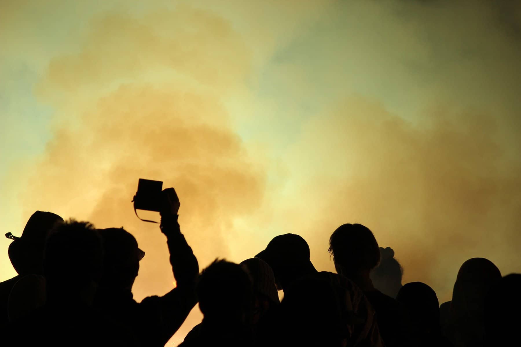 People are seen in silhouette with artificial smoke behind them.
