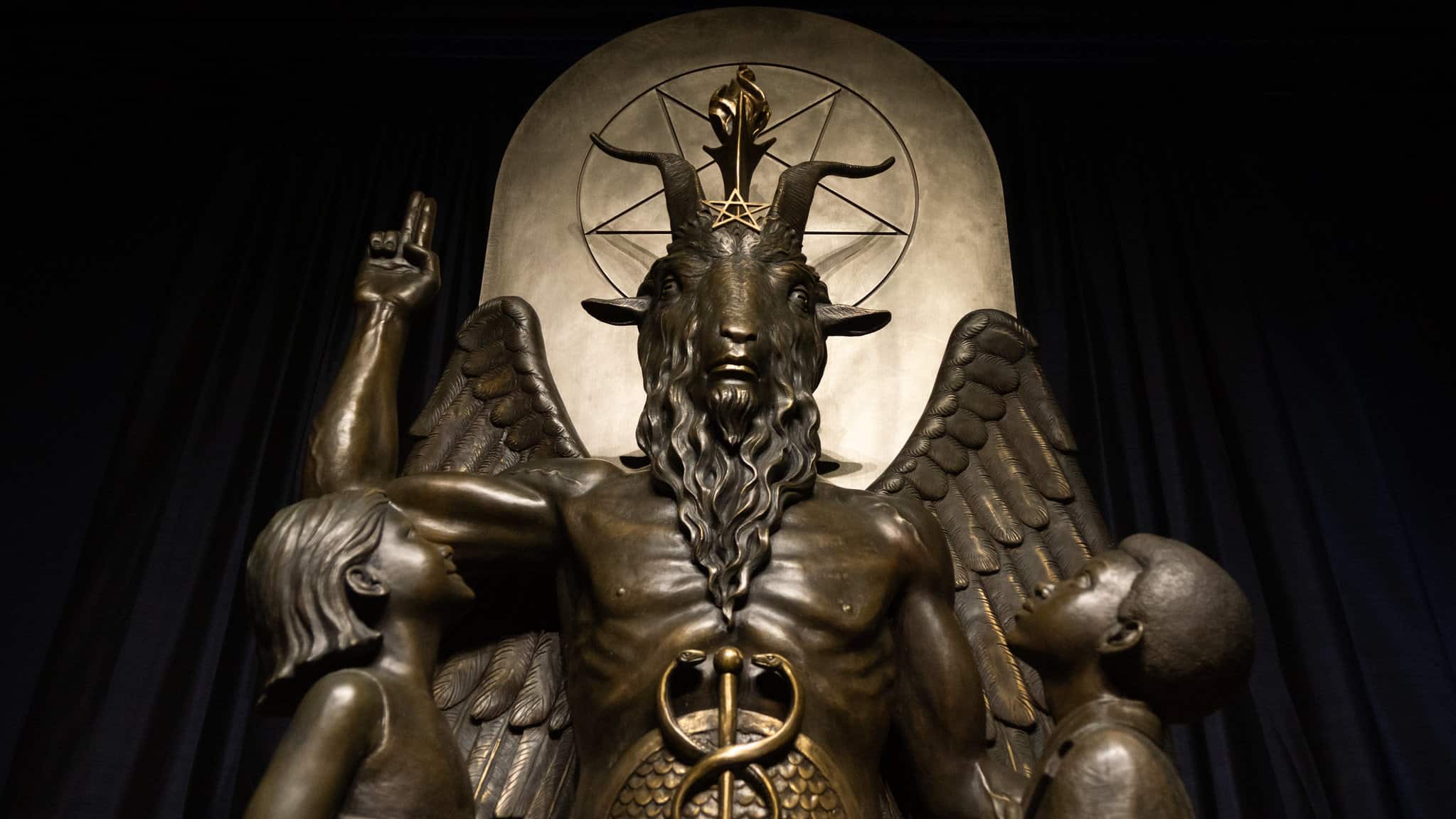 A cast bronze figure is shown appearing to be half man, half goat with wings. A pentagram is between the horns on it's head.
