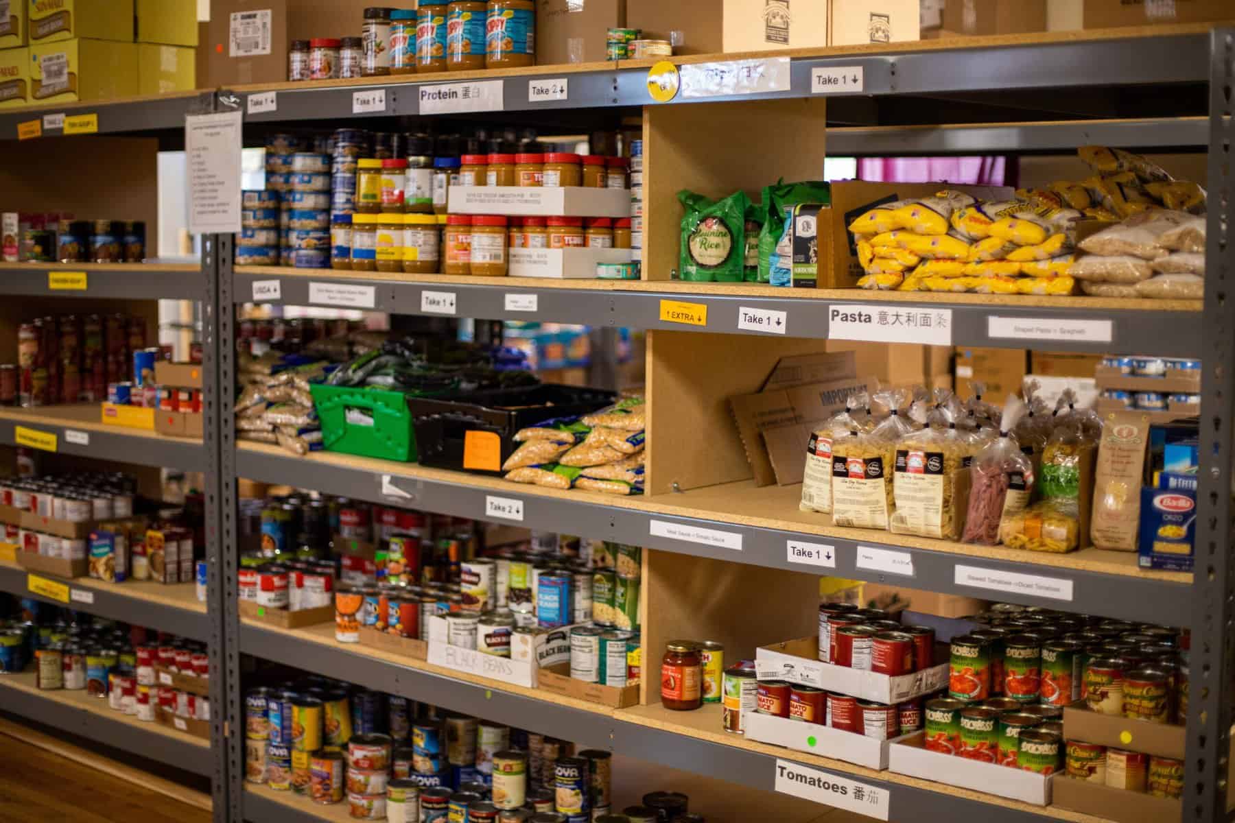 A variety of food items line the shelves of a donation center.