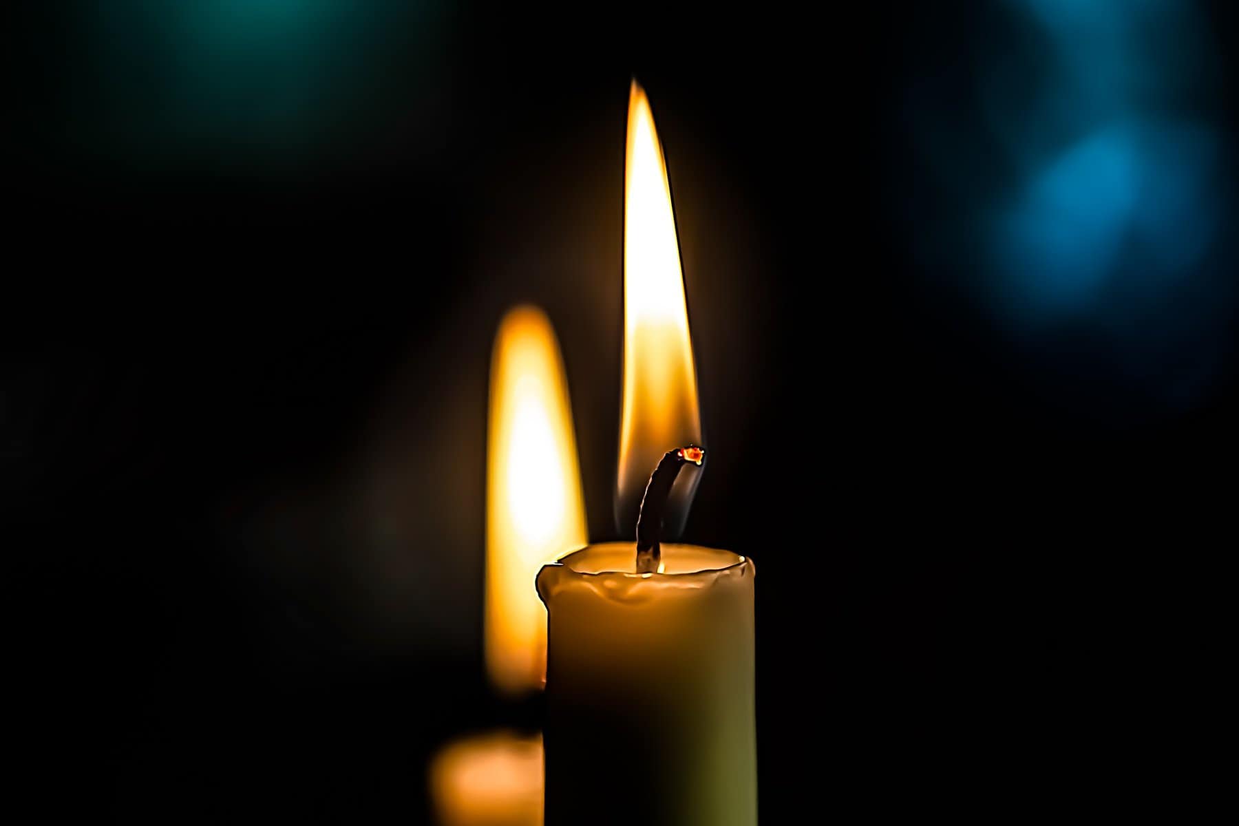 A tapered candle is shown lit with another behind it and lower.