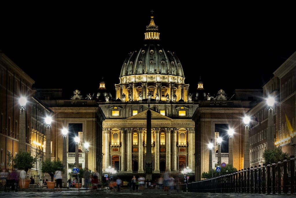 The dome of the Vatican is seen straight on from the street at night.
