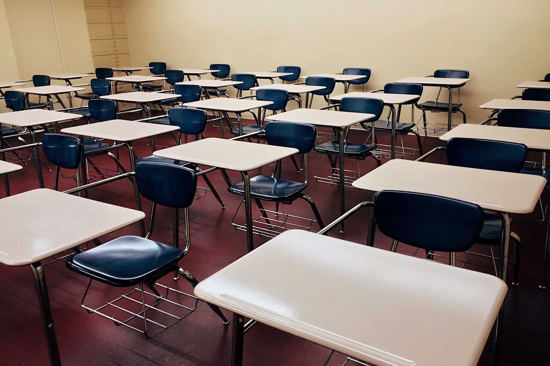 A schoolroom filled with desks and chairs is shown.