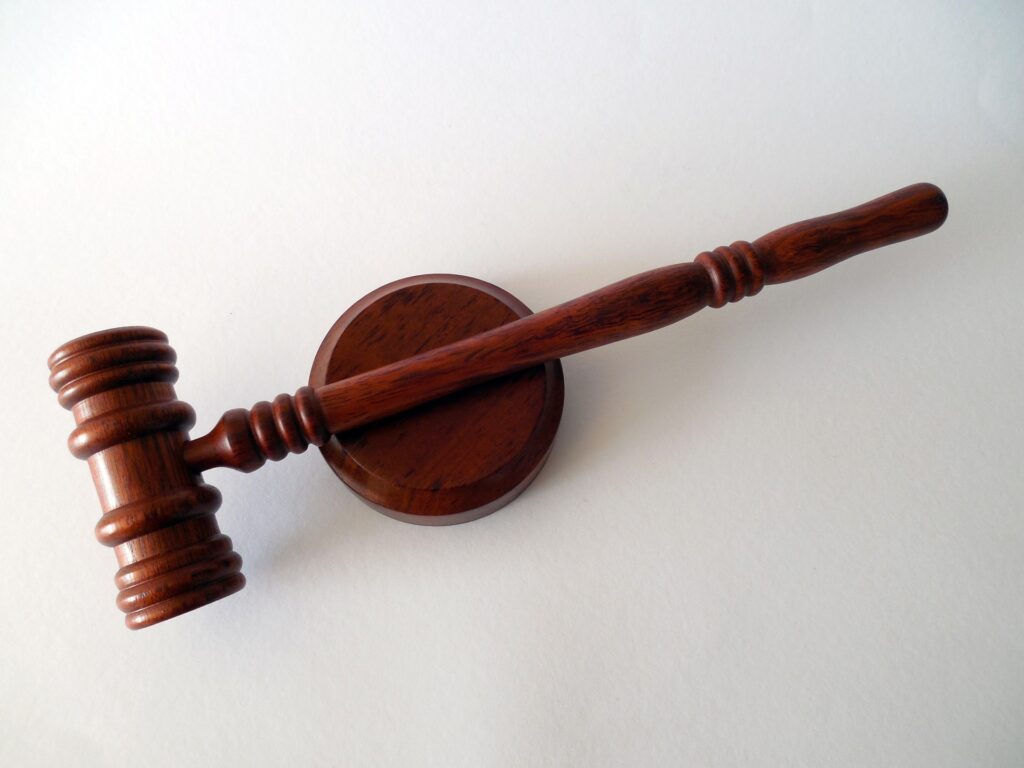 A brown wooden gavel and it's pedestal are shown from directly above against a white background.