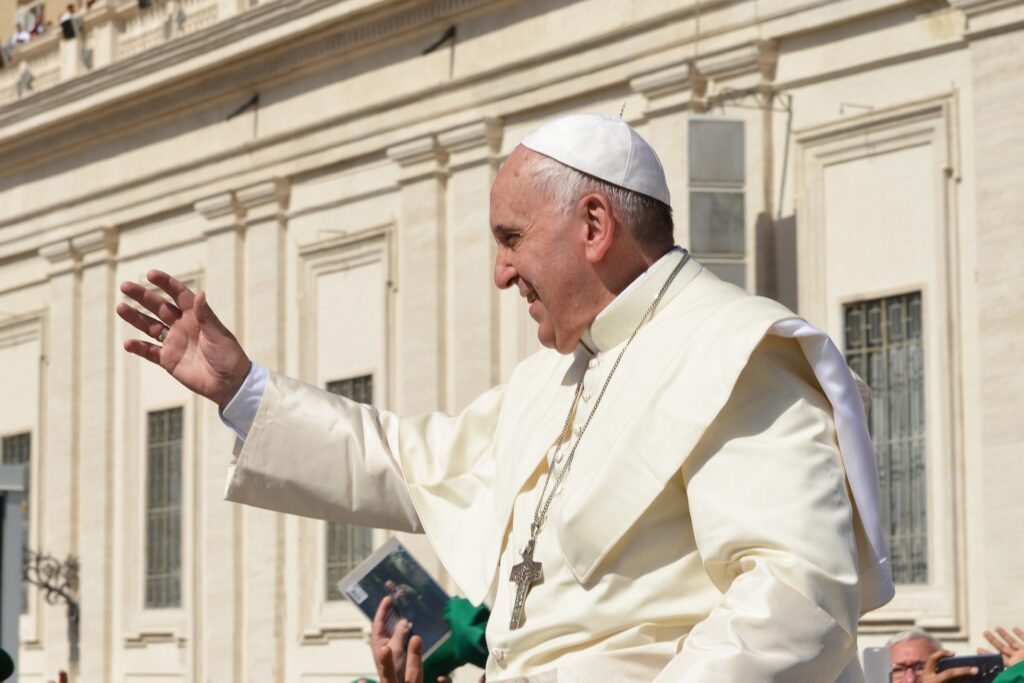Pope Francis waves to an outdoor crowd.