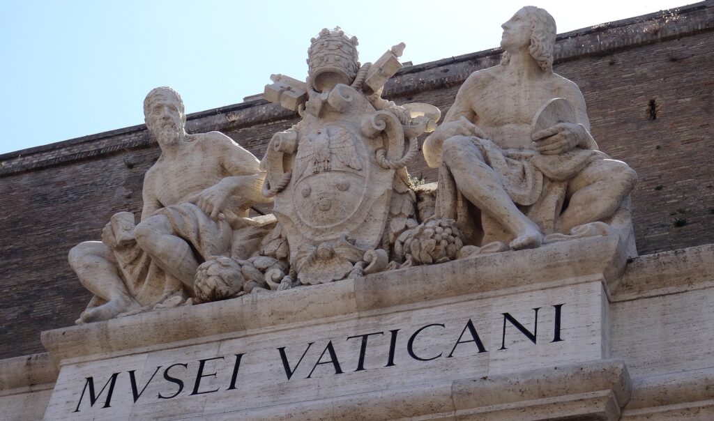 The carved entrance with three figures to the Vatican Museums is shown.