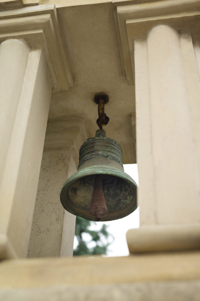 A church bell is shown close up hanging in a steeple.