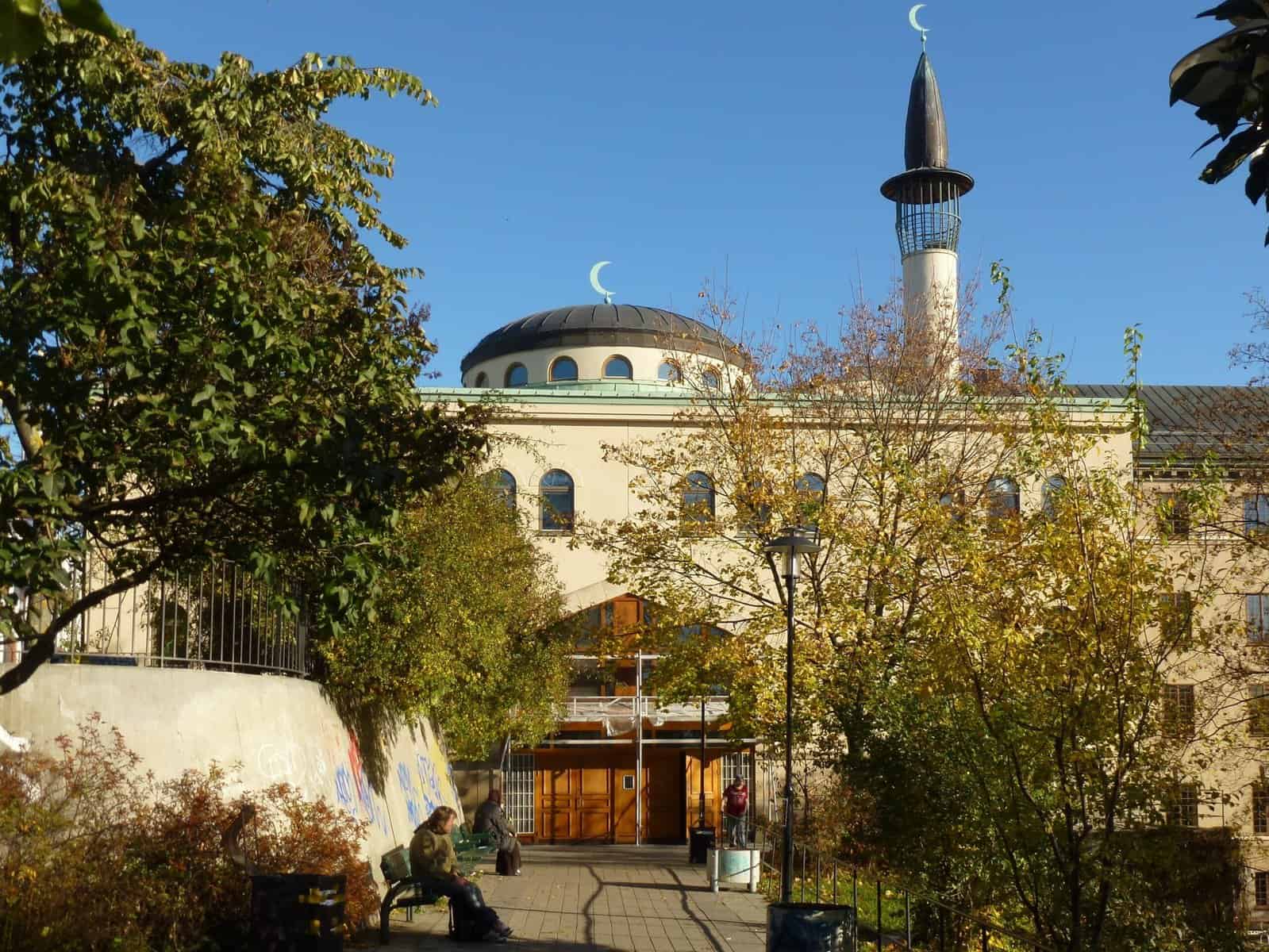 A mosque in Stockholm is shown from the street and partly obscured by trees.